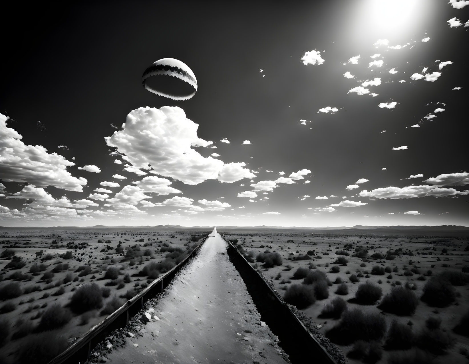 Grayscale desert road with large surreal baseball in cloudy sky