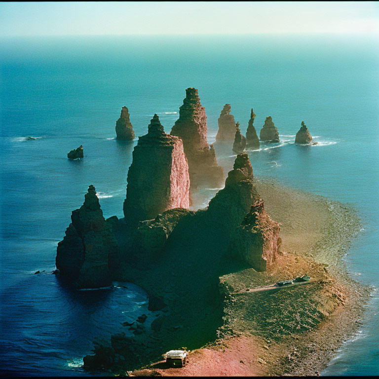 Rugged coastline with towering sea stacks and parked vehicle by the shore