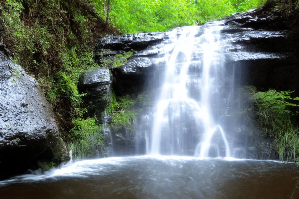 Tranquil waterfall flowing over mossy rocks in lush setting