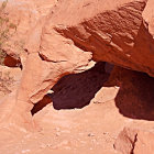 Vibrant red and orange desert landscape with surreal rock formations and floating specks