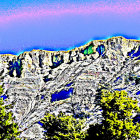 Colorful desert landscape with rock formations and greenery under clear sky