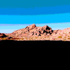 Desert landscape with mountains, blue skies, and sand dunes.