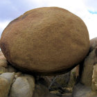 Textured dome rock formation overlooking canyon with water and cliffs under blue sky