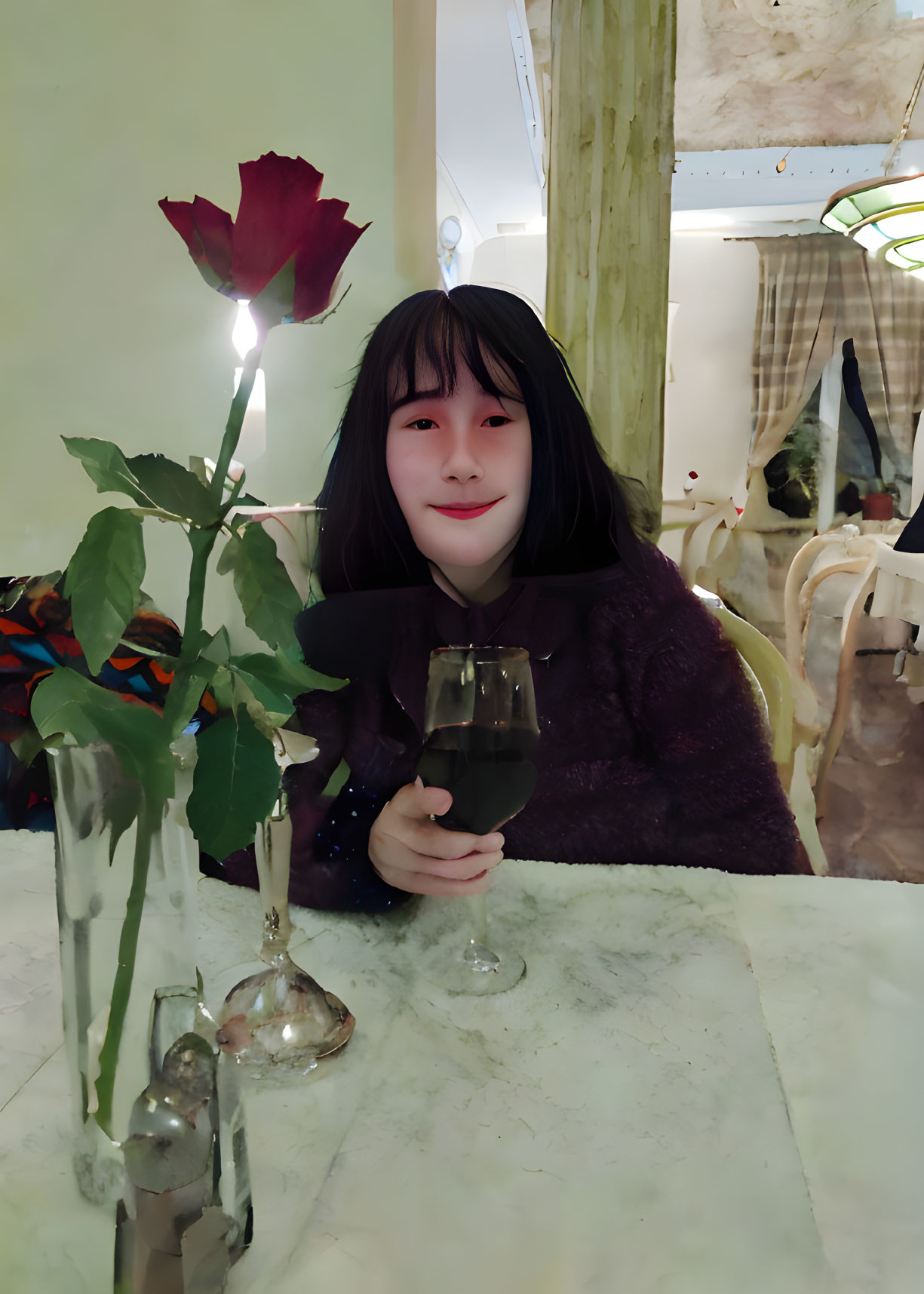 Smiling person with drink and rose at warmly lit table