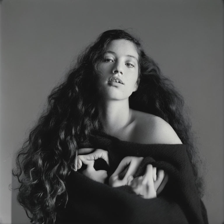 Monochrome portrait of woman with long, wavy hair and elegant hand pose