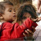 Vintage clothing children huddle with red hoods, one whispers, elderly hand offers berries