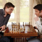 Men with beards in vintage attire play chess in serene forest