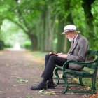 Person reading book on park bench surrounded by lush greenery and flowers