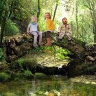 Vintage-attired children on wooden bridge in forest oasis