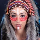 Person with Intricate Face Paint and Feathered Headdress in Colorful Beads