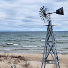 Traditional Wooden Windmill on Sandy Beach Overlooking Blue Sea