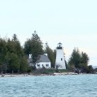 Tranquil red and white lighthouse by pine forest and water reflection