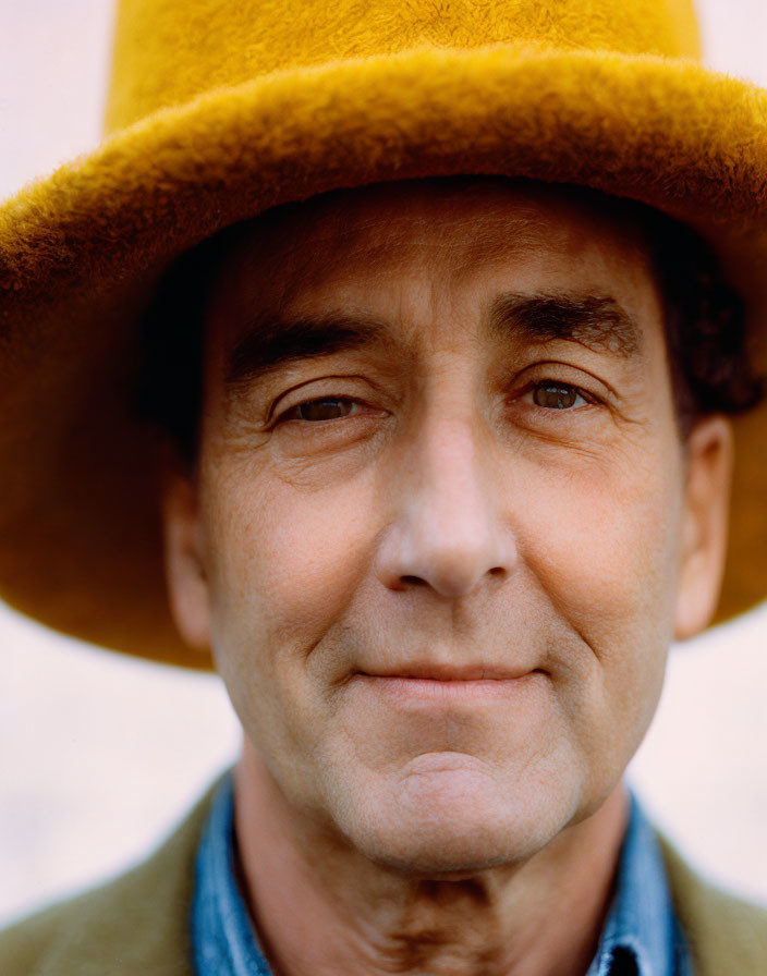 Smiling person in yellow hat and green jacket close-up