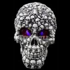 Intricate ornate skull with smaller skulls, gears, and purple elements on black background