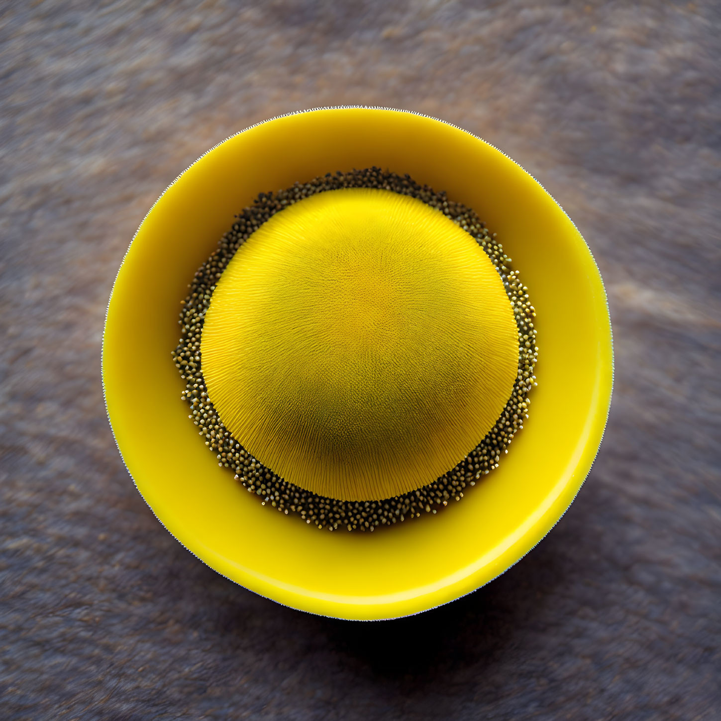 Yellow Cup with Speckled Black Seeds on Textured Surface