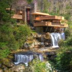 Contemporary multi-level house with glass walls in lush green surroundings, reflected on water under starry sky