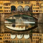 Tranquil Ponte Vecchio scene with boat and reflection in Florence