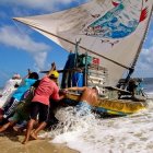 Group on sailboat battling waves under bright sky