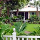 White House Surrounded by Green Foliage and Red Flowers