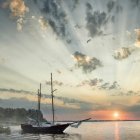 Sailboats on calm waters at sunset with vibrant sky and clouds