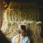 Blonde young girls sitting among hay bales with somber expressions