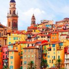 Vibrant town illustration with colorful buildings, tower, trees, and birds