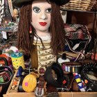 Creepy doll with large eyes, disheveled hair, vintage dress, and skull in decrepit