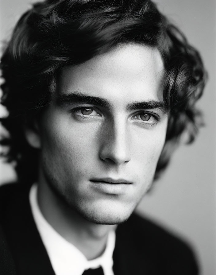 Monochrome portrait of young man in suit and tie with curly hair