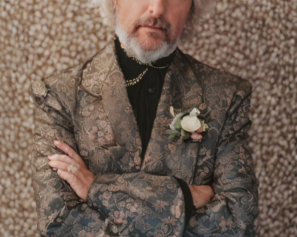 White-haired man in patterned suit with crossed arms on textured background