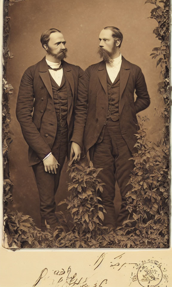 Victorian men with beards posing identically in front of foliage