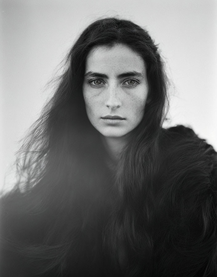 Monochrome portrait of person with long dark hair and intense gaze