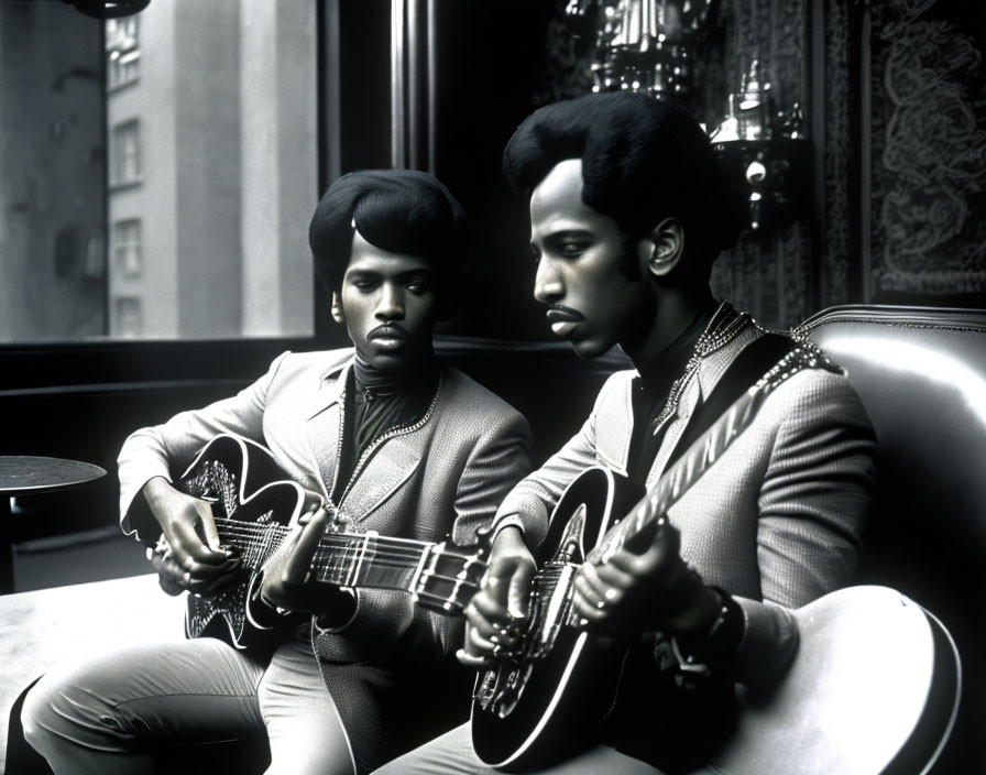 Two people with afro hairstyles playing guitars in embellished suits - black and white photo