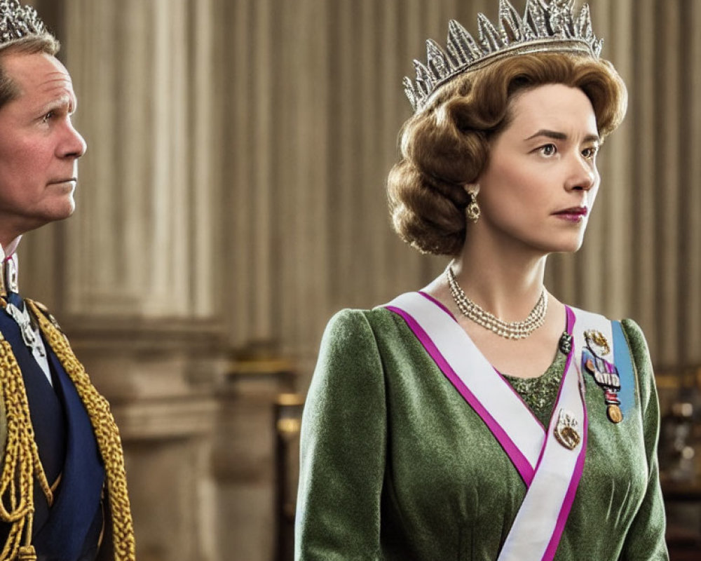 Regal man and woman in crowns and sashes with serious expressions