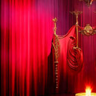 Luxurious Red Theater Curtains with Golden Tassels and Elegant Chandelier in Spotlight Setting