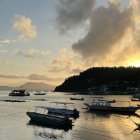 Tranquil harbor scene with boats at sunset in blue, gold, and black tones