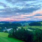 Surreal landscape with green hills, whimsical trees, and day-to-night sky