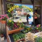 Colorful fruit and vegetable market stall under canopy on sunny day