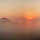 Stylized landscape painting with rolling hills, trees, castle, and sunset sky