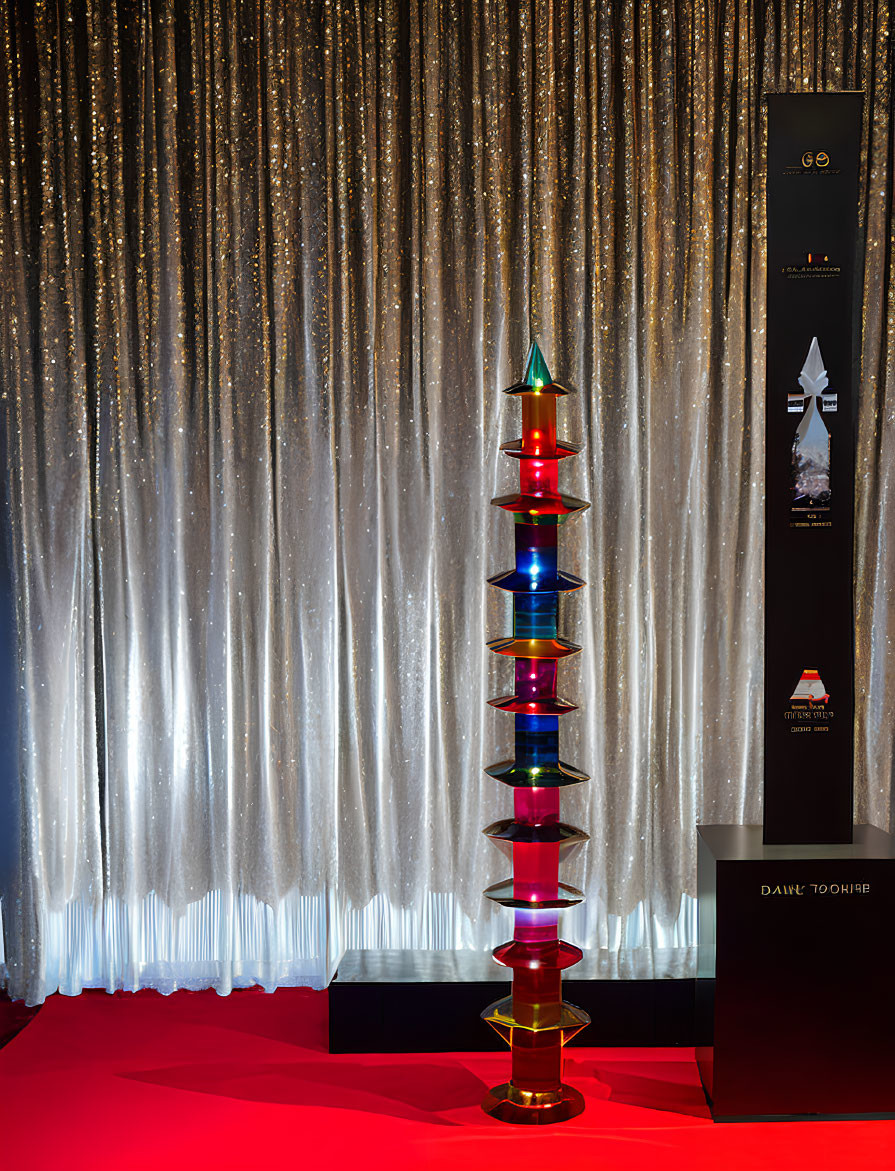 Colorful Glass Sculpture on Silver Curtain Backdrop with Red Floor and Information Stand