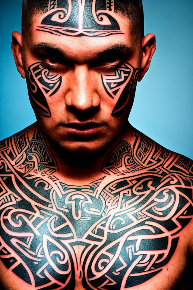 Man with intricate black tribal tattoos on face and body on blue background