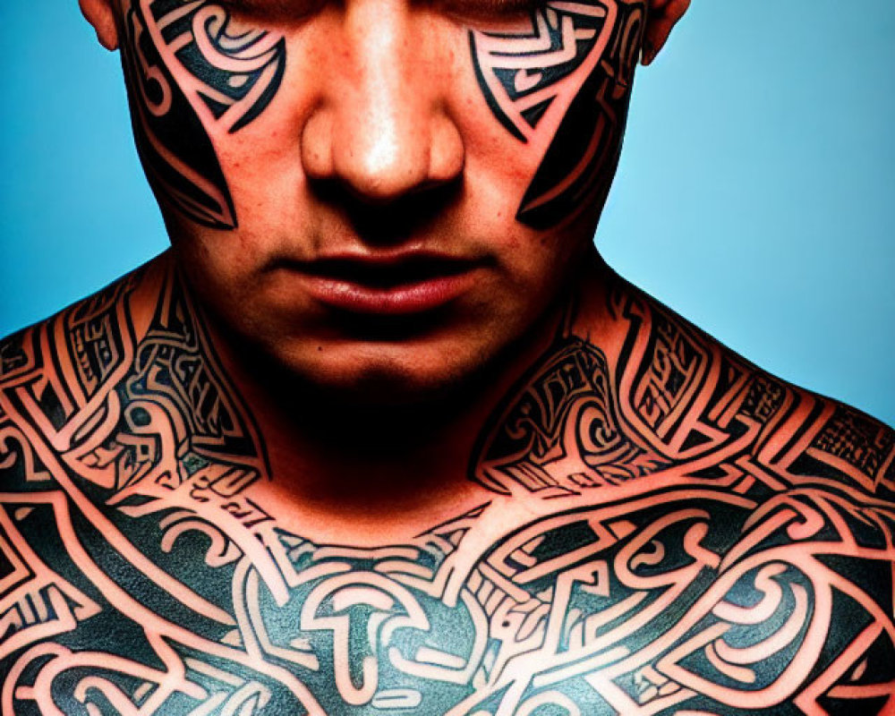 Man with intricate black tribal tattoos on face and body on blue background