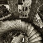 Intricate spiral staircase with wrought iron railings and stained glass floor pattern