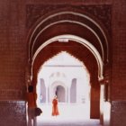 Ornate archway leading to dome-topped building in sepia and purple tones