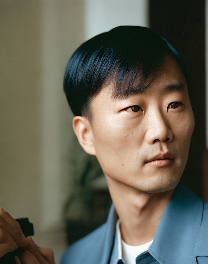 Contemplative man in blue suit with angular haircut near soft window light