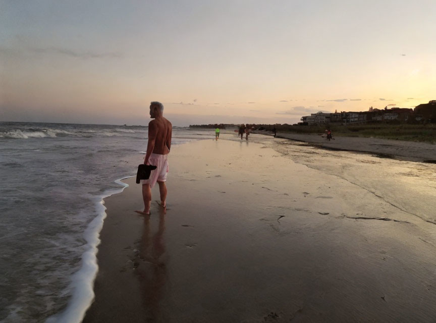 Individual on beach at dusk with ocean view and cloudy sky.