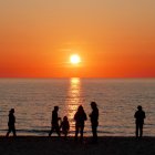 Five People Silhouettes on Beach at Sunset with Orange Sky