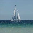 Billowing white sails on sailing ship at dawn in calm waters