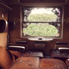 Empty train cabin with leather seats, wooden table, serene landscape view