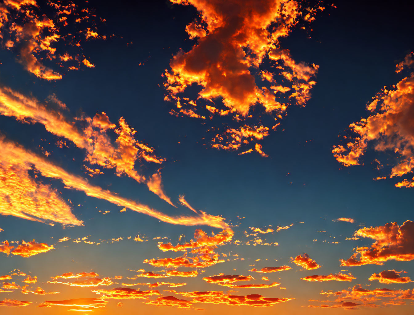 Vibrant sunset sky with orange and red clouds on deep blue background