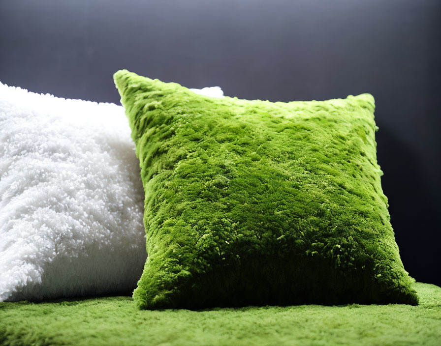 White and green plush pillows on matching surface against dark background